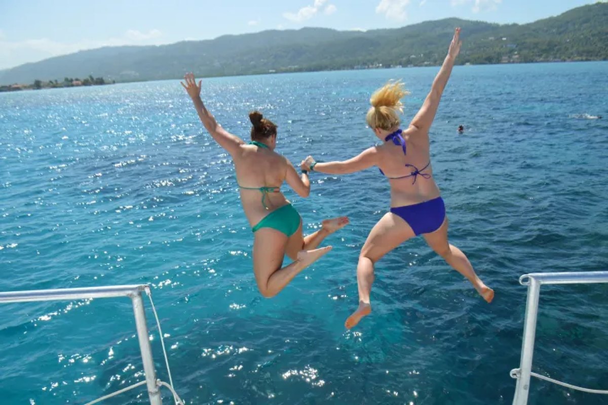 Turistas saltando al mar desde un catamarán frente a la costa de Jamaica