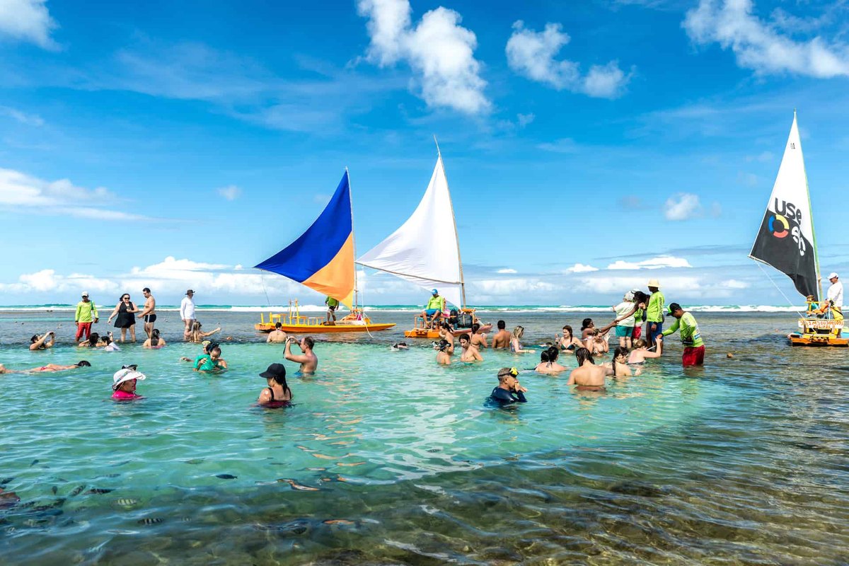 Turistas en las piscinas naturales de Porto de Galinhas junto a jangadas tradicionales